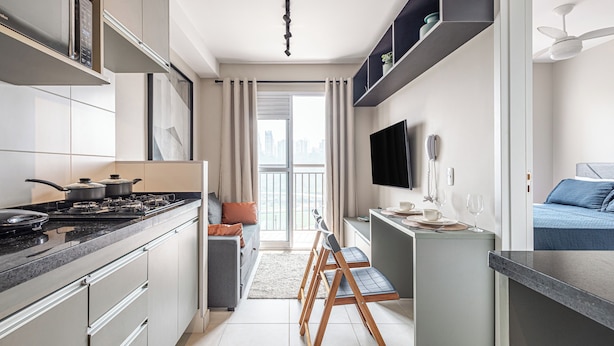 Una cocina moderna con estufa, armarios y un comedor con sillas.