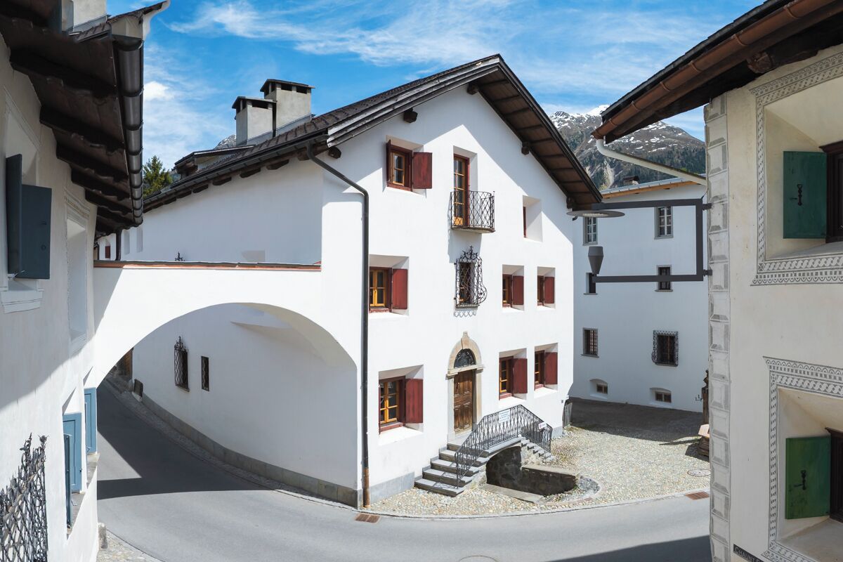 A white building with a balcony, a staircase, and a small courtyard.
