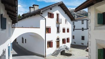 A white building with a balcony, a staircase, and a small courtyard.