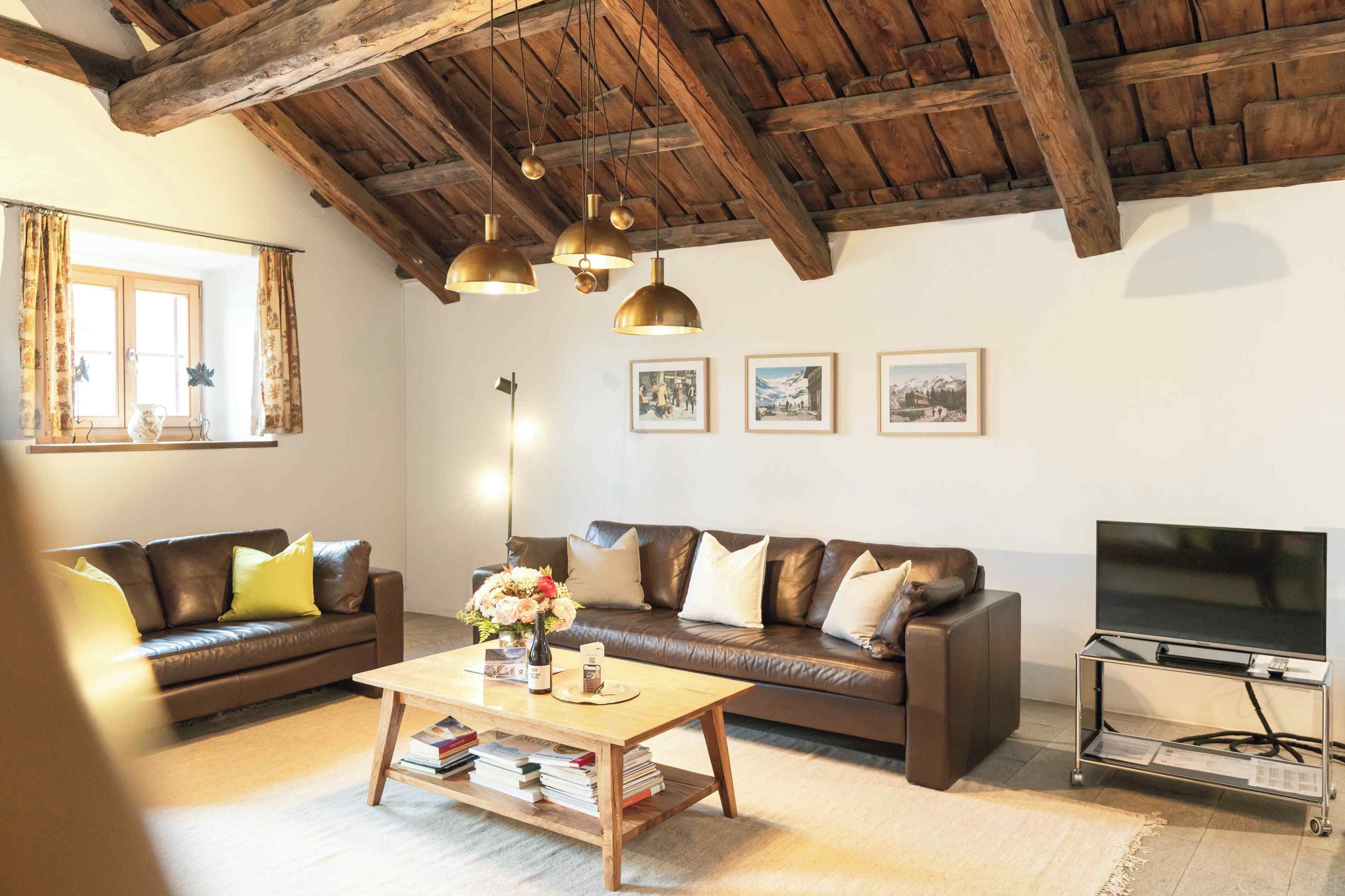 Un salon avec un canapé en cuir marron, une table basse en bois et un téléviseur posé sur un meuble métallique.