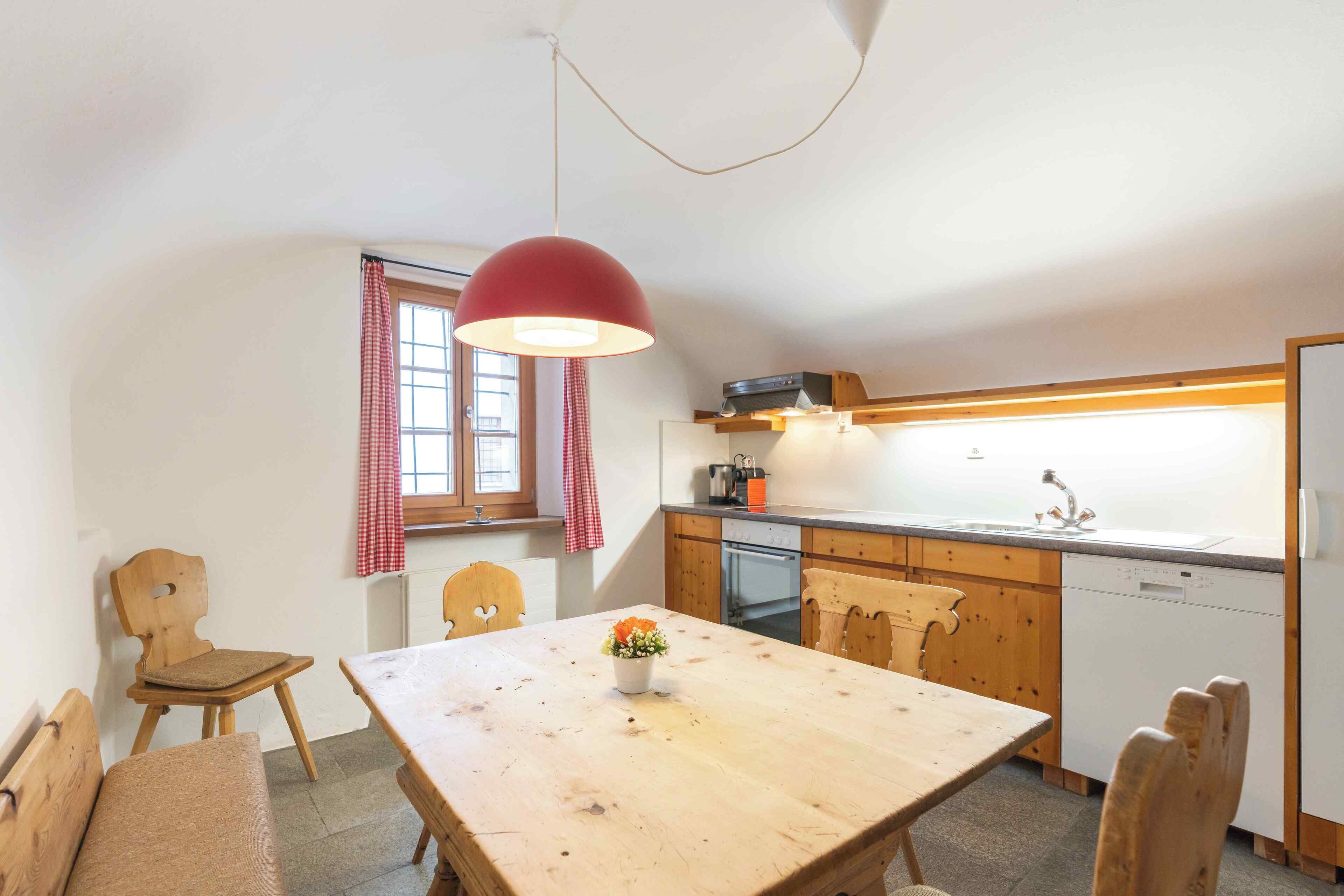 A kitchen with wooden cabinets, a sink, and a dining table with chairs.