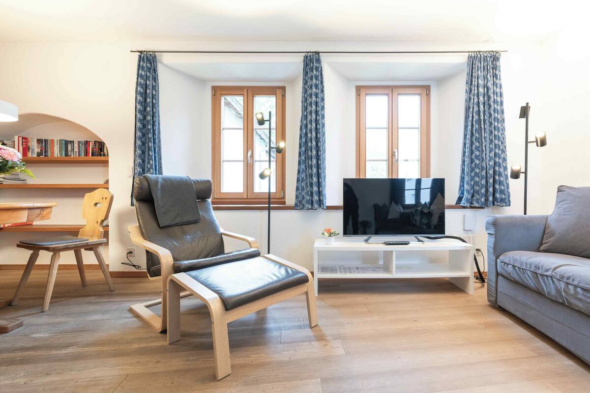A living room with a sofa, a chair, a TV, and a bookshelf.