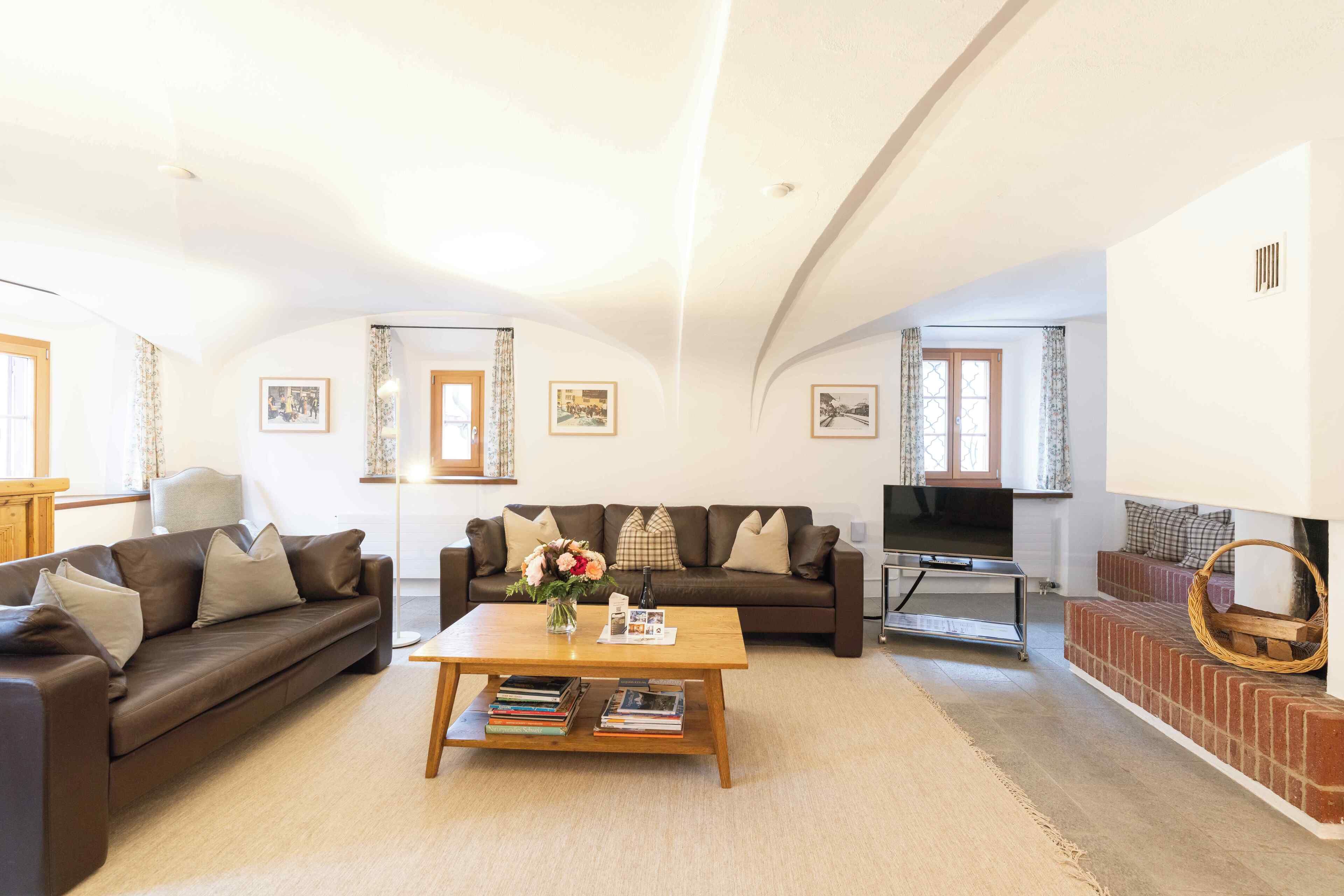 A spacious living room with two sofas, a coffee table, and a fireplace.