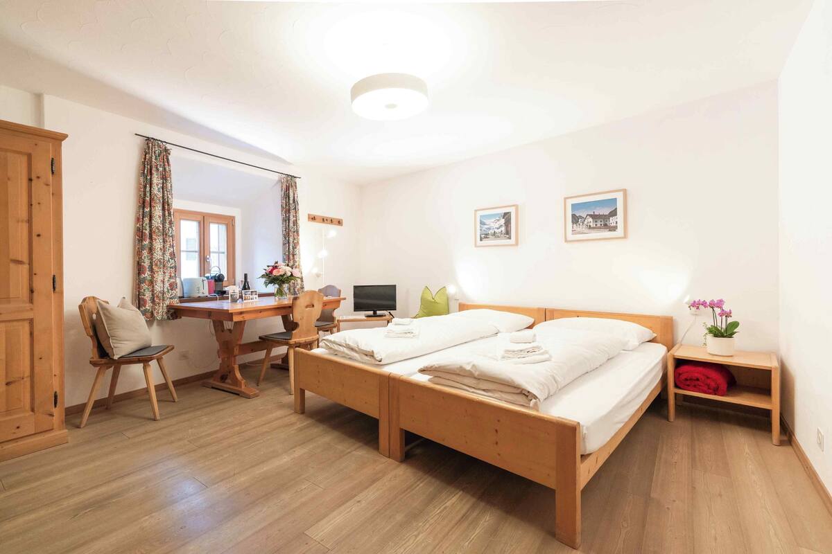 A room with two wooden beds, a desk with a computer, a chair, and a wardrobe.