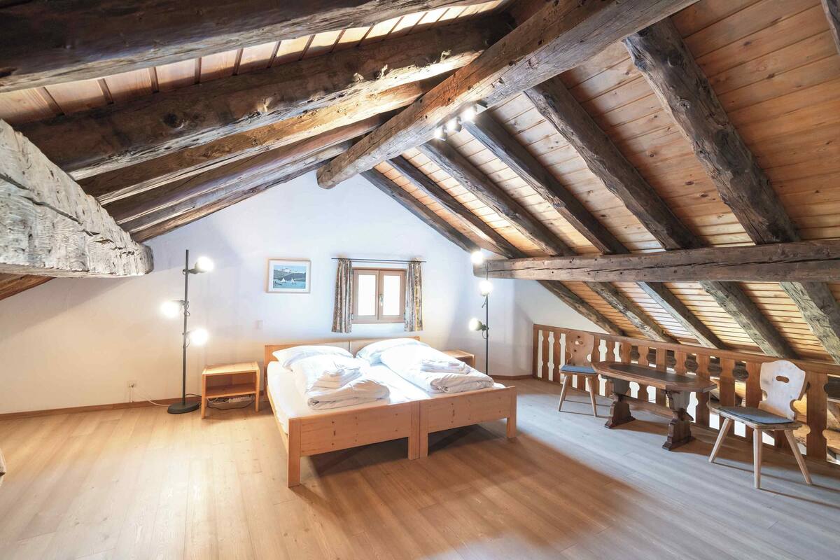 A bedroom with a wooden bed, a nightstand, a floor lamp, and a bench.
