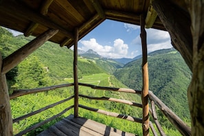 Una cabaña de madera con vistas a un valle exuberante y montañas.