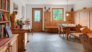 Un interior de madera con una mesa de comedor, sillas, una estantería y una puerta con ventanal.