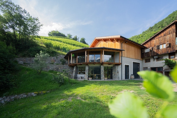 Una casa moderna de dos pisos con base de piedra, estructura superior de madera y un balcón.