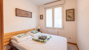 A neatly made bed with pillows and a folded blanket, a bedside table with a lamp, and two framed pictures on the wall. - Cosy Stay in Barèges – Mountain Views, Wi-Fi, Free Parking, Near Ski Slopes (Barèges)
