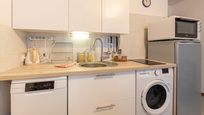 A compact kitchen with a dishwasher, washing machine, microwave, and a sink with modern fixtures. - Cosy Stay in Barèges – Mountain Views, Wi-Fi, Free Parking, Near Ski Slopes (Barèges)