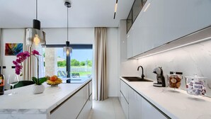 A modern kitchen with a central island, a built-in oven, and a large window offering a view of the outdoors. - Amazing home in Nedescina (Nedescina)