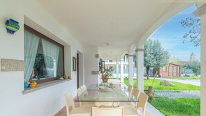 A glass-top dining table with chairs, a potted plant, and a window with curtains. - Room 'Perla' with Shared Pool, Wi-Fi and Air Conditioning (Torpè)