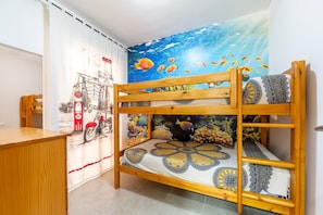 Un lit superposé avec une couvre-lit à motifs, un bureau et une fresque murale.