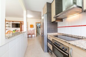 Une cuisine moderne dotée d’un réfrigérateur en acier inoxydable, d’un four encastré et de plans de travail en granit.
