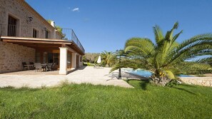 A stone building with a balcony, outdoor seating, and a palm tree. - Country House 'Horlandis Ref 133' with Mountain View, Private Pool and Wi-Fi (Son Servera)
