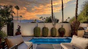 Un área de piscina con sillones de descanso y plantas en macetas.
