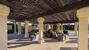 Un área de patio techada al aire libre con arreglos de asientos y una estructura de pérgola.