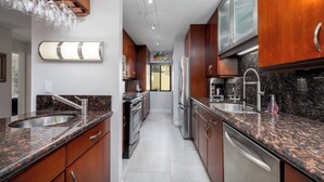 Una cocina moderna con encimeras de granito, electrodomésticos de acero inoxidable y armarios de madera.