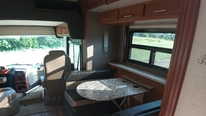 An RV interior with a kitchen area, seating, and a window providing a view of the outdoors. - Luxury 2-bedroom RV in fabulous Woodbury with WiFi, AC (Woodbury)