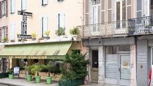 A hotel with a green awning, a sign for 'St. Vincent Hotel Restaurant,' and a closed shop with a metal gate.