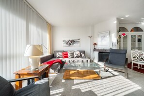 Ein modernes Wohnzimmer mit einer Couch, einem Glastisch und einem Kamin.