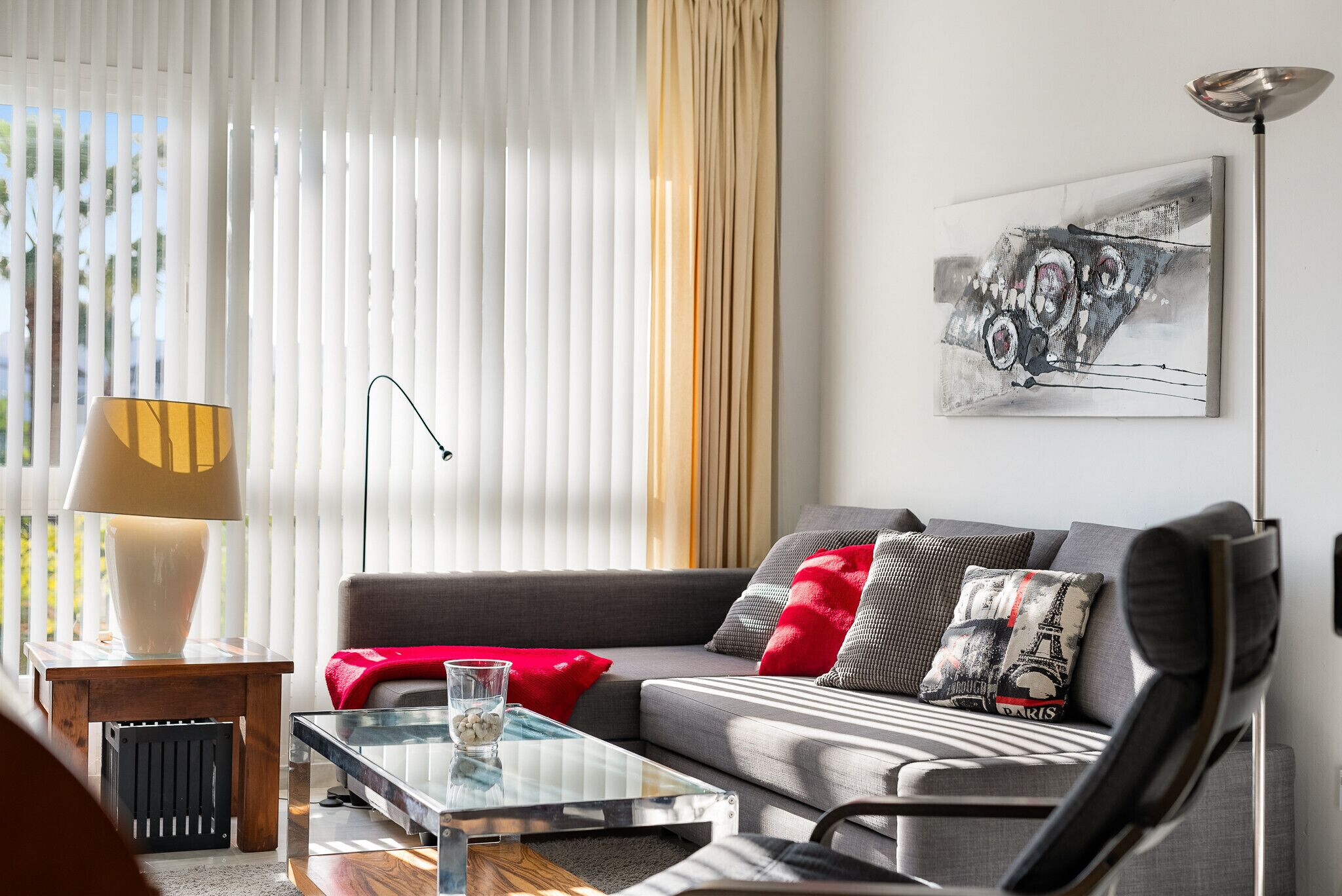 A modern living room with a sofa, a glass coffee table, and a lamp.