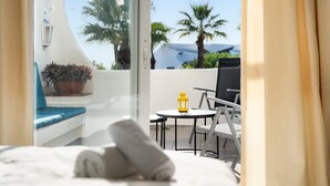 Een balkon met een bed, een tafeltje, een stoel en een bloempot.