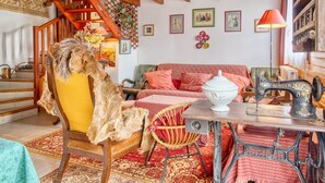 A cozy room with a wooden staircase, a vintage Singer sewing machine, a green sofa, and a chair with a fur throw. - Charming House with Large Garden – Perfect for Families, Near Pool, Tennis & Nature (La Roche-Chalais)