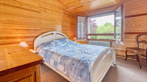 A wooden-paneled bedroom with a bed, a window, a chair, and a table. - Charming House with Large Garden – Perfect for Families, Near Pool, Tennis & Nature (La Roche-Chalais)