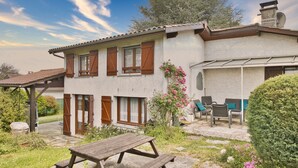 A house with a patio, a wooden table, and chairs. - Charming House with Large Garden – Perfect for Families, Near Pool, Tennis & Nature (La Roche-Chalais)