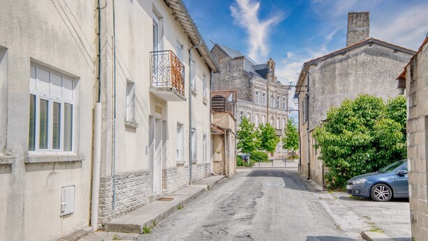 A narrow street lined with buildings, a parked car, and a clear sky. - Charming House with Large Garden – Perfect for Families, Near Pool, Tennis & Nature (La Roche-Chalais)