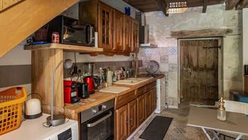 Una cucina con mobili in legno, un forno a microonde, un lavello e un piano cottura.