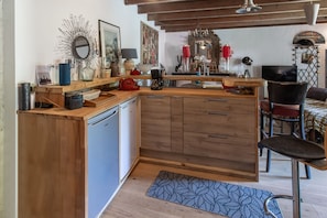 A kitchen with wooden cabinets, a dishwasher, and a dining area with a table and chairs.