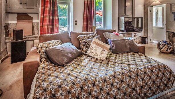 Ein gemütliches Zimmer mit einem geblümten Bett, Holzschränken und einem kleinen Tisch mit Fernseher.