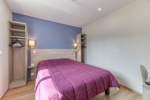 Un dormitorio con cama, armario empotrado, lámparas de noche y escritorio con silla.