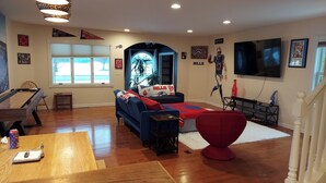 A living room with a pool table, a blue sofa, and a red chair.