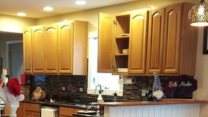 A kitchen with wooden cabinets, a black backsplash, and a countertop with a sink.