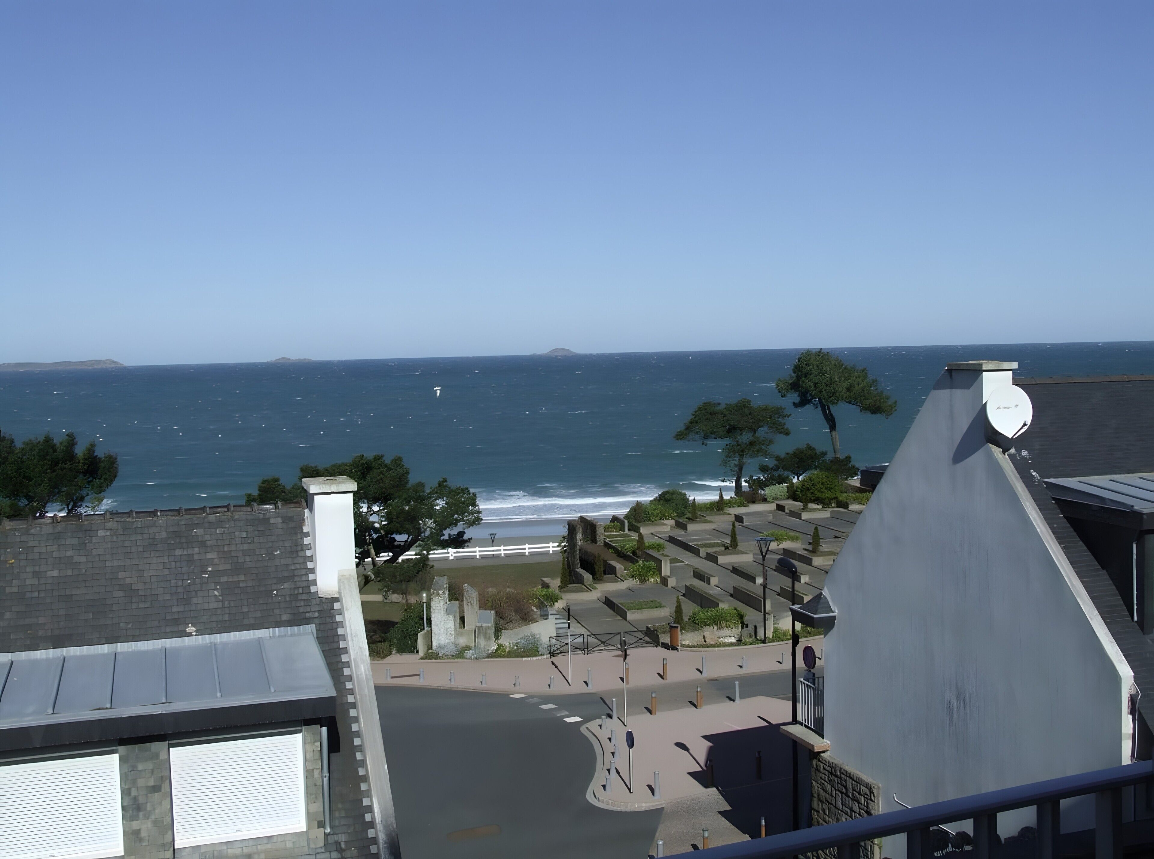 A coastal view with a cemetery, clear sky, and distant landmass.