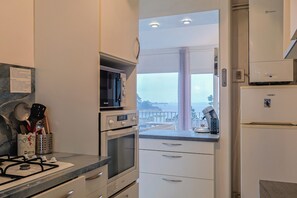 Une cuisine moderne équipée d’une cuisinière à gaz, d’un four, d’un four à micro-ondes et offrant une vue sur la ville grâce à une grande fenêtre.