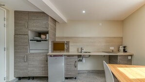 A compact kitchen with a refrigerator, microwave, sink, and a wooden dining table. - Apartment 'Pmr' - Logis les forges (Arvillard)
