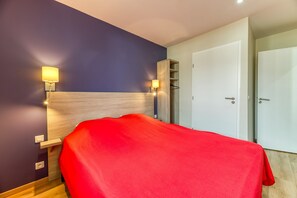 Ein Hotelzimmer mit einem Bett, zwei Wandleuchten, einem Kleiderschrank und einer Tür.