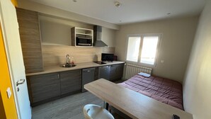Una cucina compatta con forno a microonde, lavello e un piccolo angolo ristoro con sgabelli.