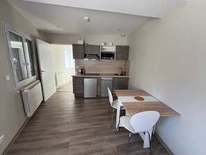 Una cucina moderna con forno a microonde integrato, lavastoviglie e lavello. C'è una zona pranzo con tavolo e sedie.
