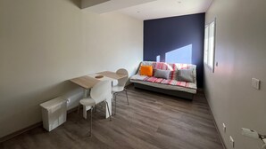 Quarto moderno com mesa de jantar, cadeiras, sofá e janela.