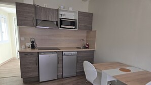 Uma cozinha moderna com eletrodomésticos embutidos, lava-louças e uma área de refeições com mesa e cadeiras.