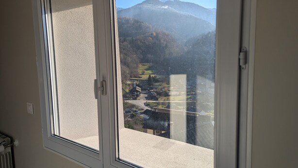 Janela com vista para um vale, uma montanha e uma igreja.