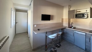 Eine moderne Küche mit integriertem Mikrowellenherd, einer kleinen Spüle und einem Barhocker.
