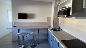 Eine moderne Küche mit Flachbildfernseher, Edelstahlspüle und Barhocker.