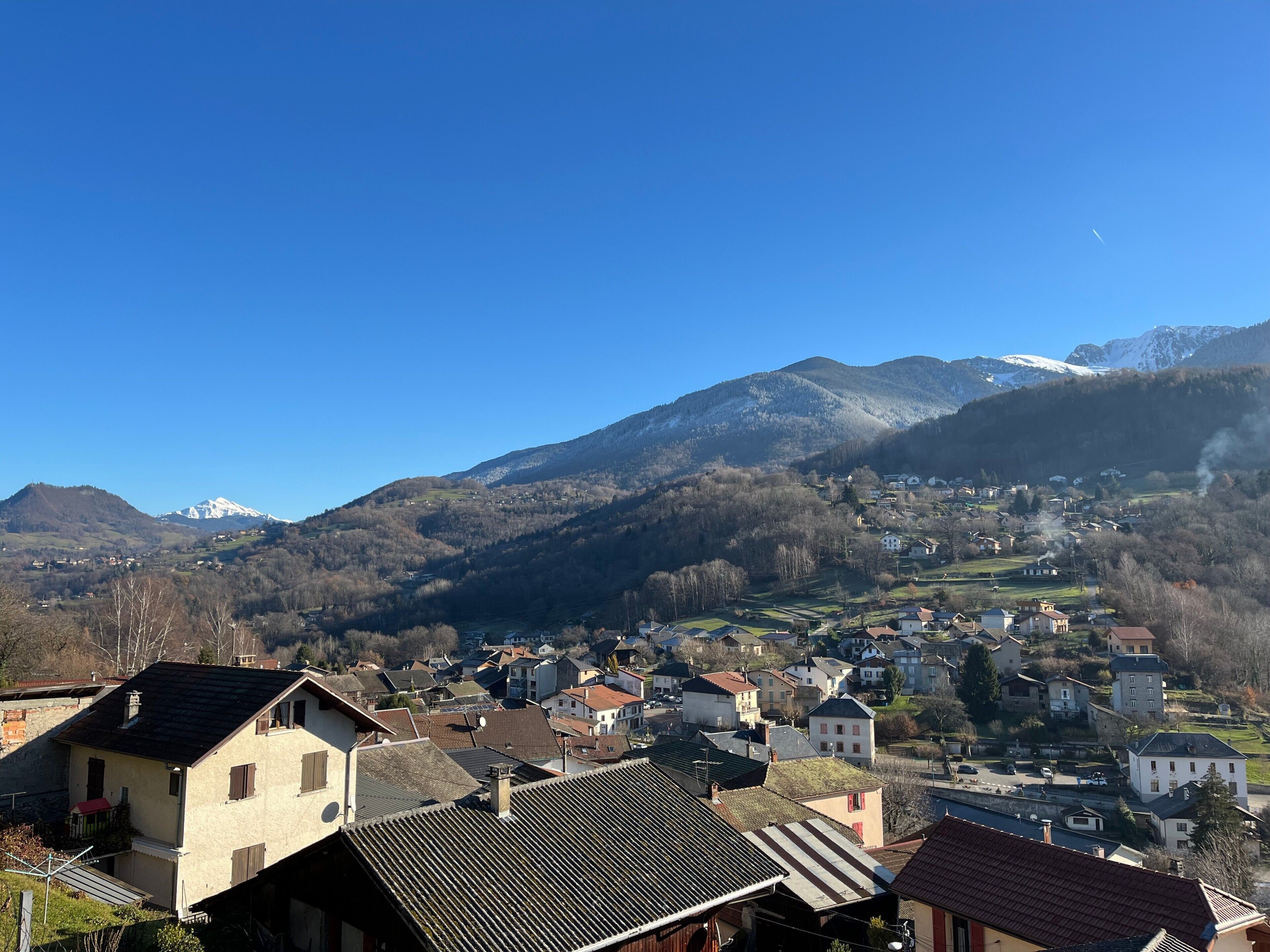 Une ville à l’architecture traditionnelle, avec une montagne en arrière-plan et un ciel dégagé.