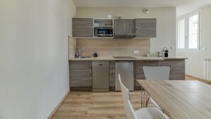 Una cuina moderna amb electrodomèstics integrats, rentaplats i zona de menjador amb taula i cadires.